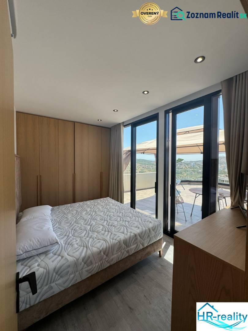 Ksamil – luxusné zariadené apartmány v Maledivách Európy - Spálňa v rekreačnom apartmáne s výhľadom z balkóna, drevený nábytok a posteľ.