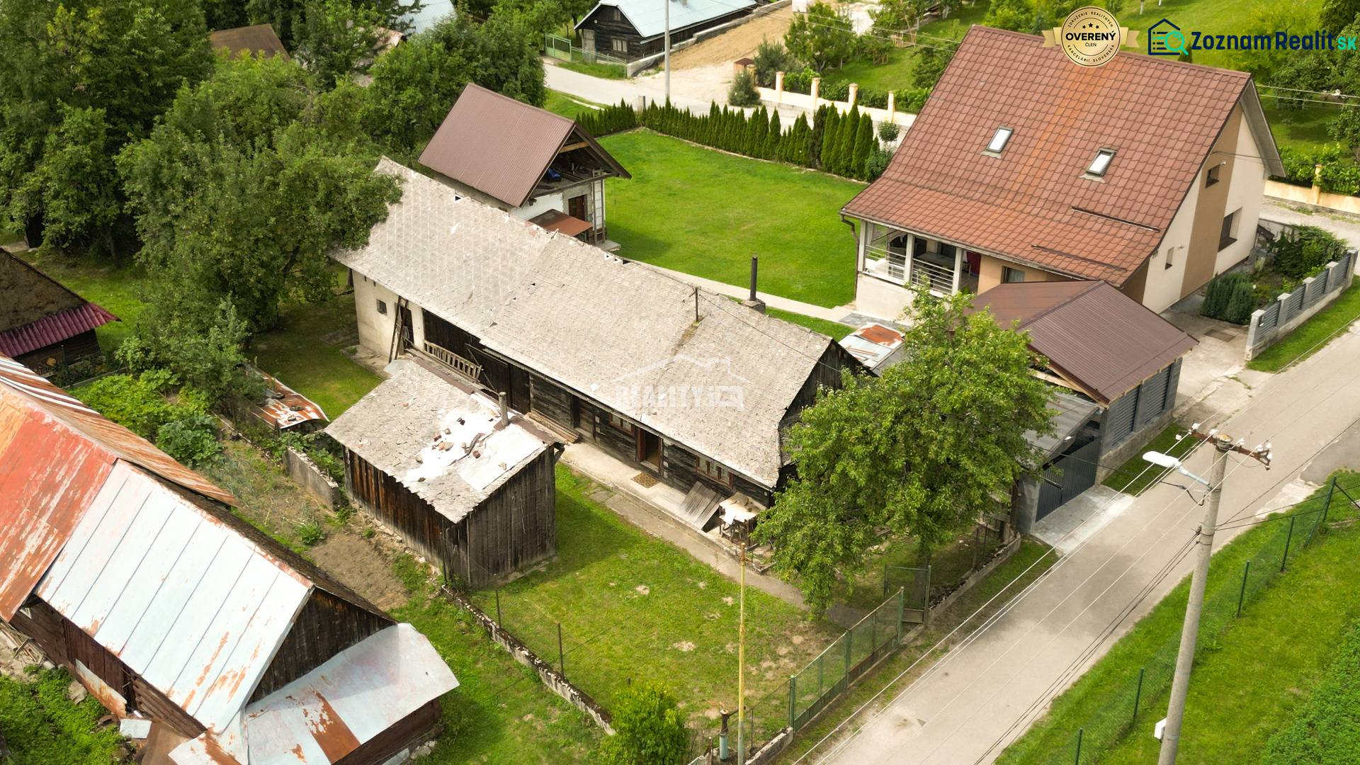 Exkluzívne na predaj drevenica s pozemkom 406 m2, Papradno - Chata v Papradne obklopená zeleňou a priľahlými stavbami z vtáčej perspektívy.