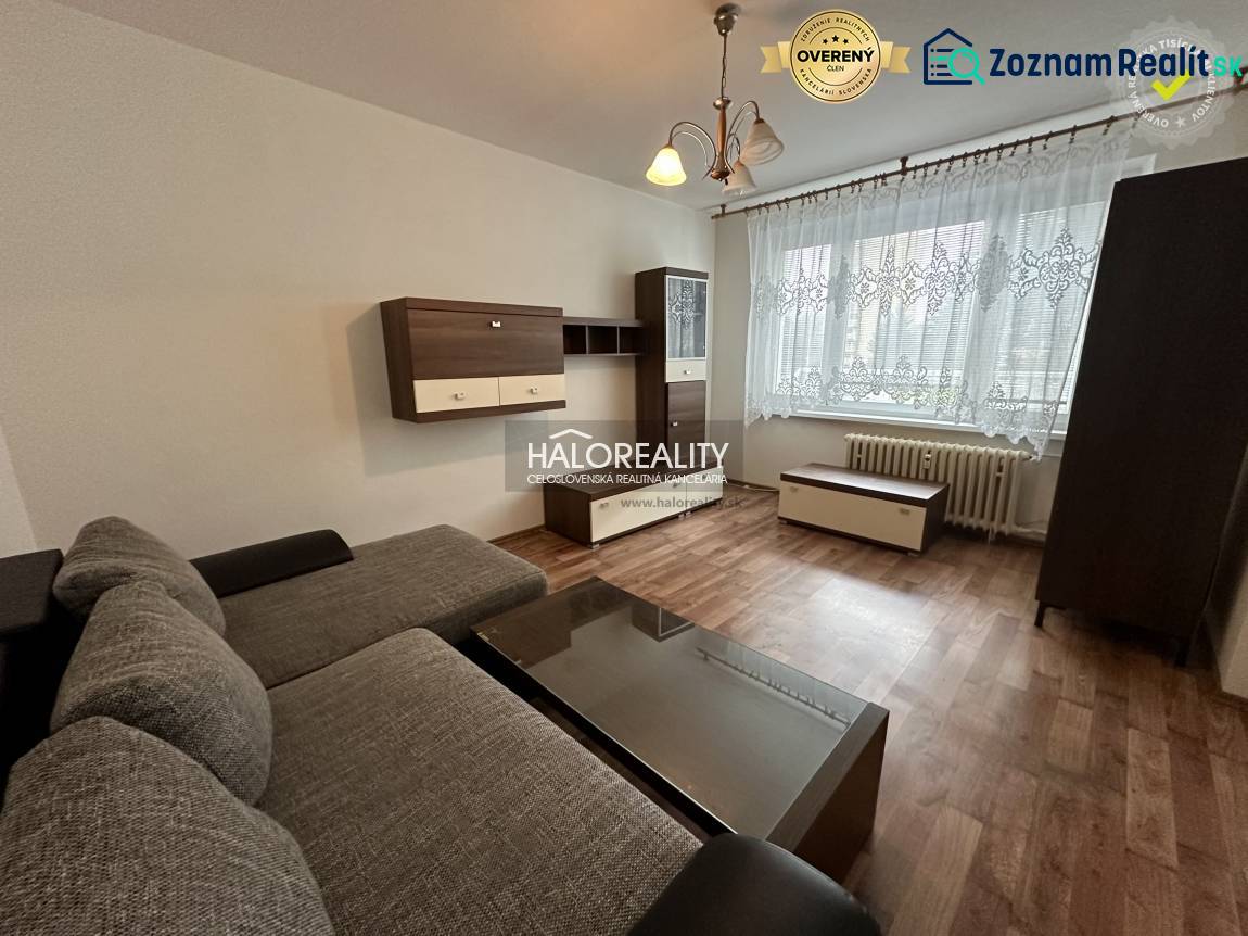 Prenájom, jednoizbový byt Rimavská Sobota, P.Hostins... - 1-izbový byt s pohovkou, dreveným nábytkom a veľkým oknom s čipkovanou záclonou.