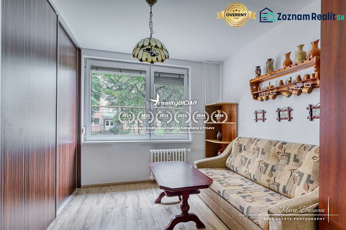 3-izbový byt v Šali na Vajanského ulici - Izba v 3-izbovom byte s pohovkou, stolíkom a podlahou s dreveným dekorom.