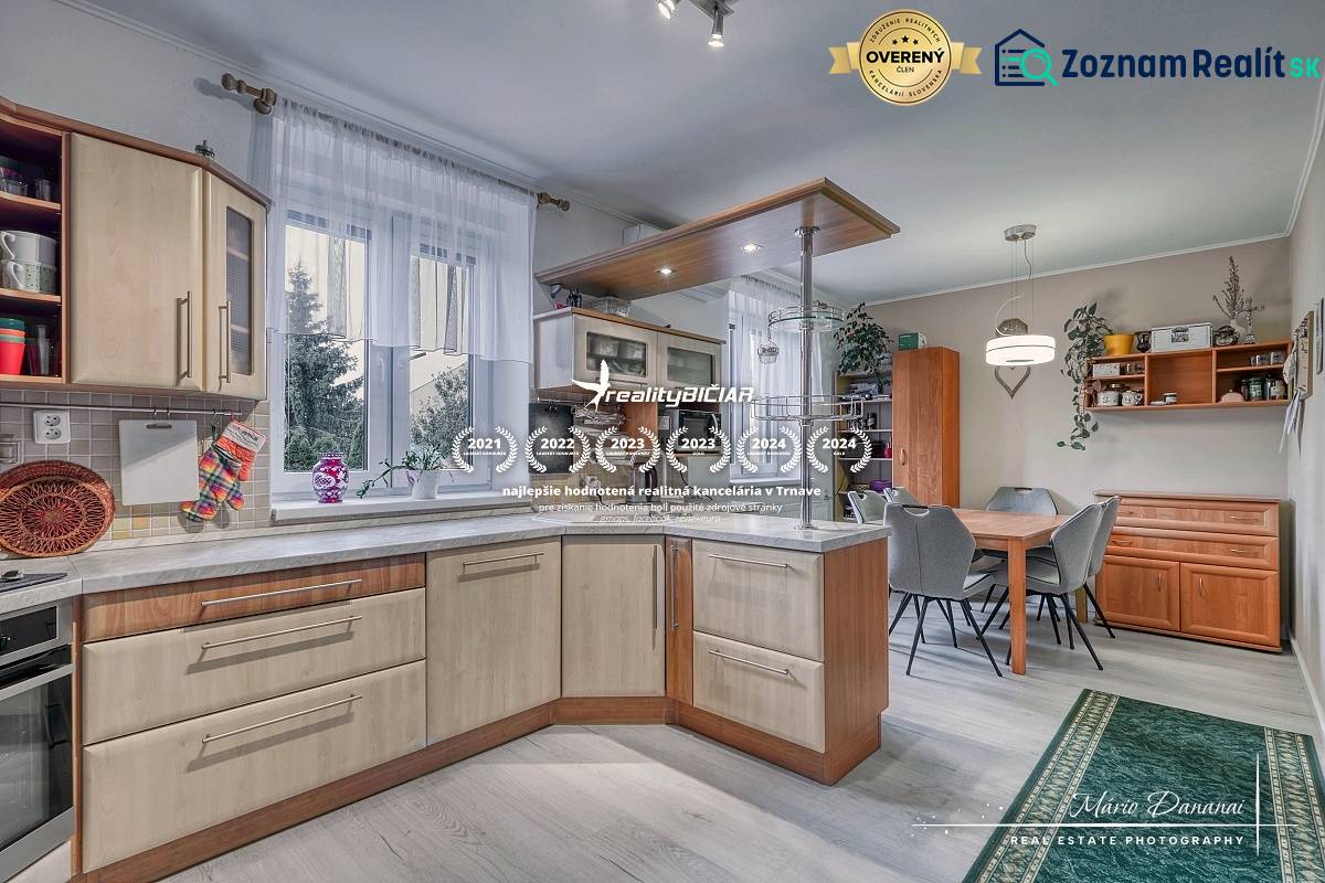 5-izbový rodinný dom s dvomi garážami v obci Špačince - Kuchyňa v rodinnom dome s podlahou s dreveným dekorom, vybavená kuchynským nábytkom.