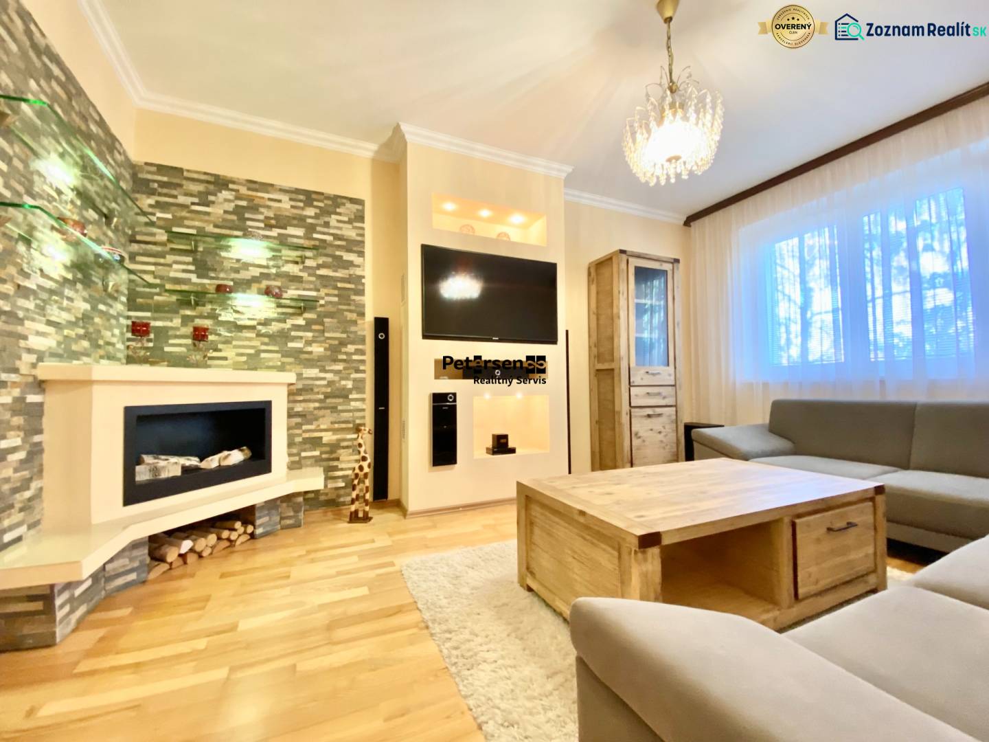 NA PRENÁJOM PRIESTRANNÝ 3-IZBOVÝ BYT V SKVELEJ LOKALITE, UL. SLOBODY - Obývačka v 3-izbovom byte s krbom, pohovkou a podlahou s dreveným dekorom.