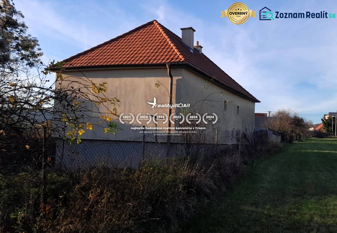 Rodinný dom v obci Dobrá Voda  - Rodinný dom v Dobrej Vode s červenou strechou a oplotením, obklopený zeleňou.