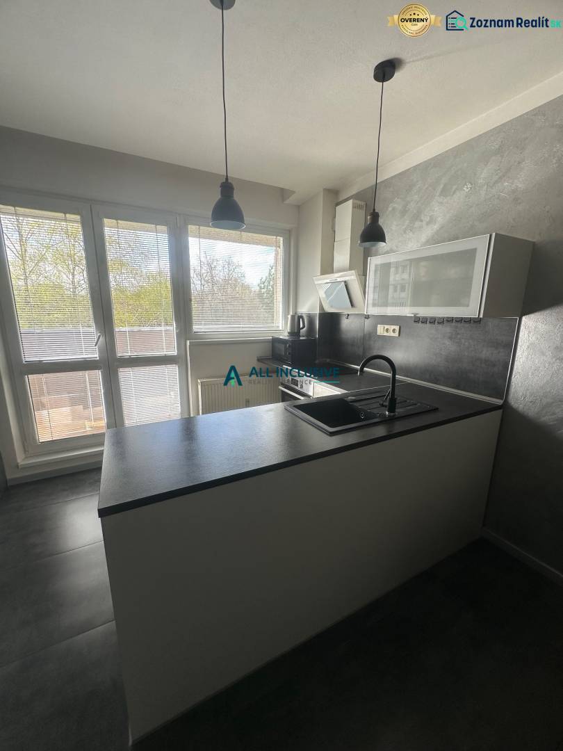 Stavbárska ulica,2-garsónka na prenájom - Kuchyňa v dvojgarsónke so sivými stenami, oknami a kuchynskou linkou.