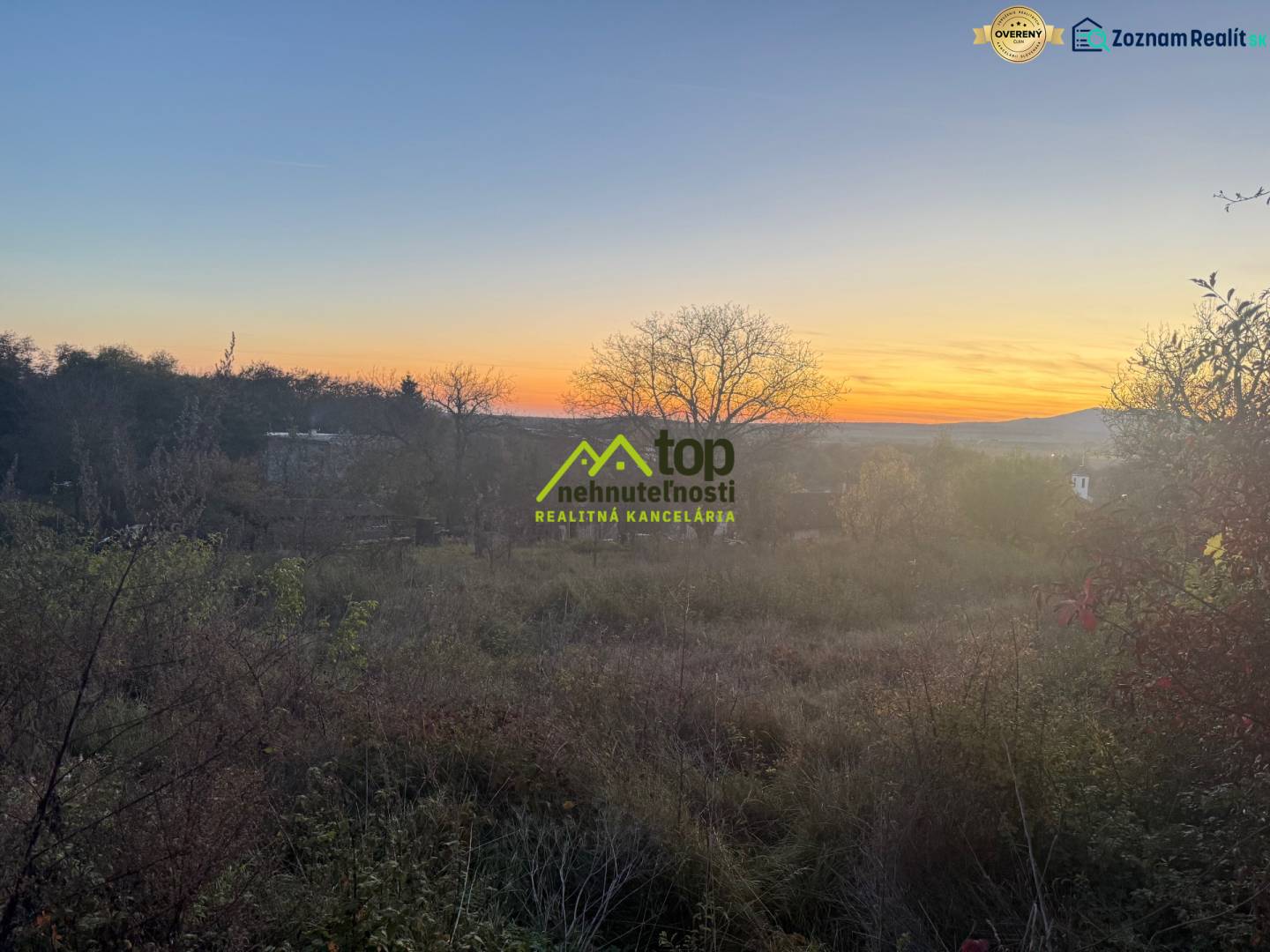 RD TVRDOMESTICE, pozemkom s prístupom z oboch strán - Západ slnka nad pokojným prírodným prostredím v Tvrdošmesticiach, jemne osvetľujúc rodinné domy.
