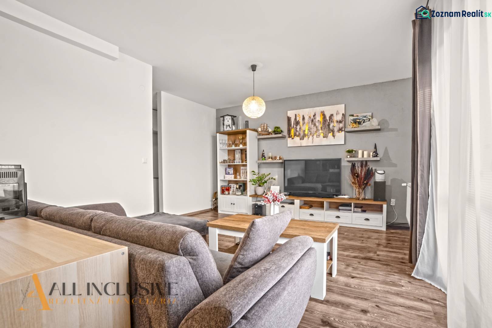 NA PREDAJ 2-IZBOVÝ BYT S 2 BALKÓNMI, DUNAJSKÁ STREDA - Obývacia izba v 2-izbovom byte s podlahou s dreveným dekorom, pohodlným sedením a dekoráciami.