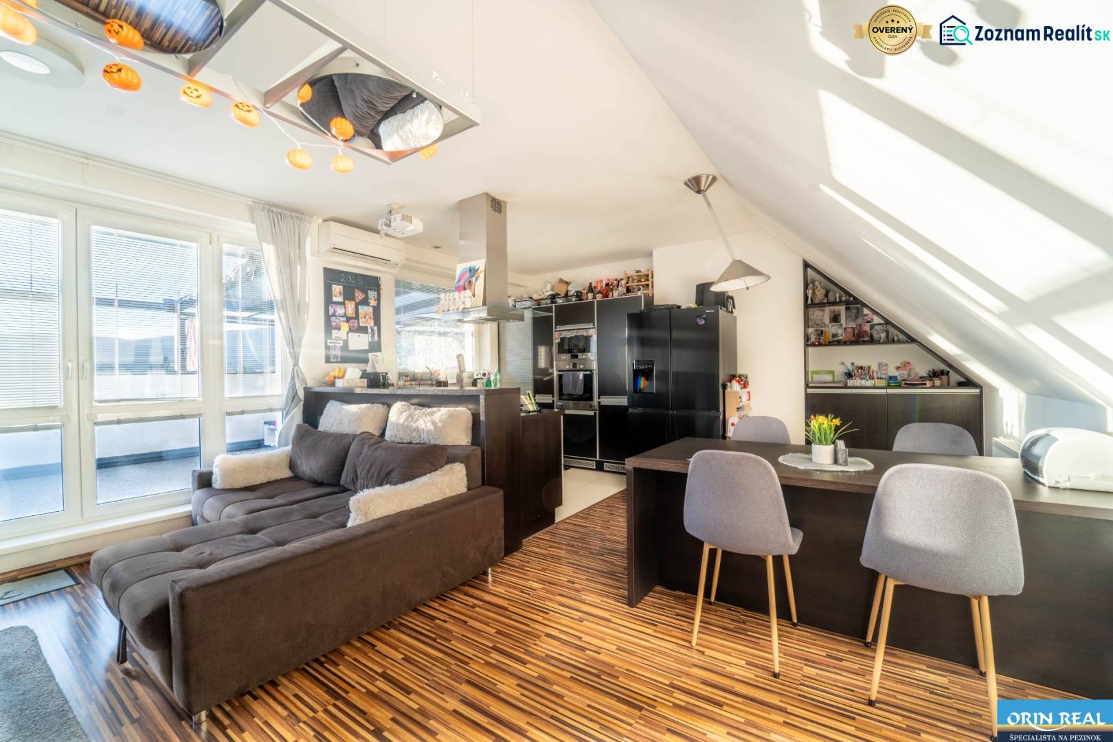 Rezervovaný!!! 2izb + terasa byt Vajanského Modra 93,8m2 - Obývačka s kuchyňou v 2-izbovom byte s podlahou s dreveným dekorom a pohodlnou sedačkou.