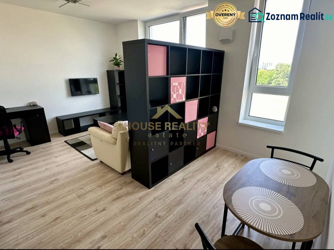 Nový 2 izbový byt SLNEČNICE, Labutia ulica, Bratislava V. Petržalka - Obývačka v 2-izbovom byte s policovou stenou a podlahou s dreveným dekorom.