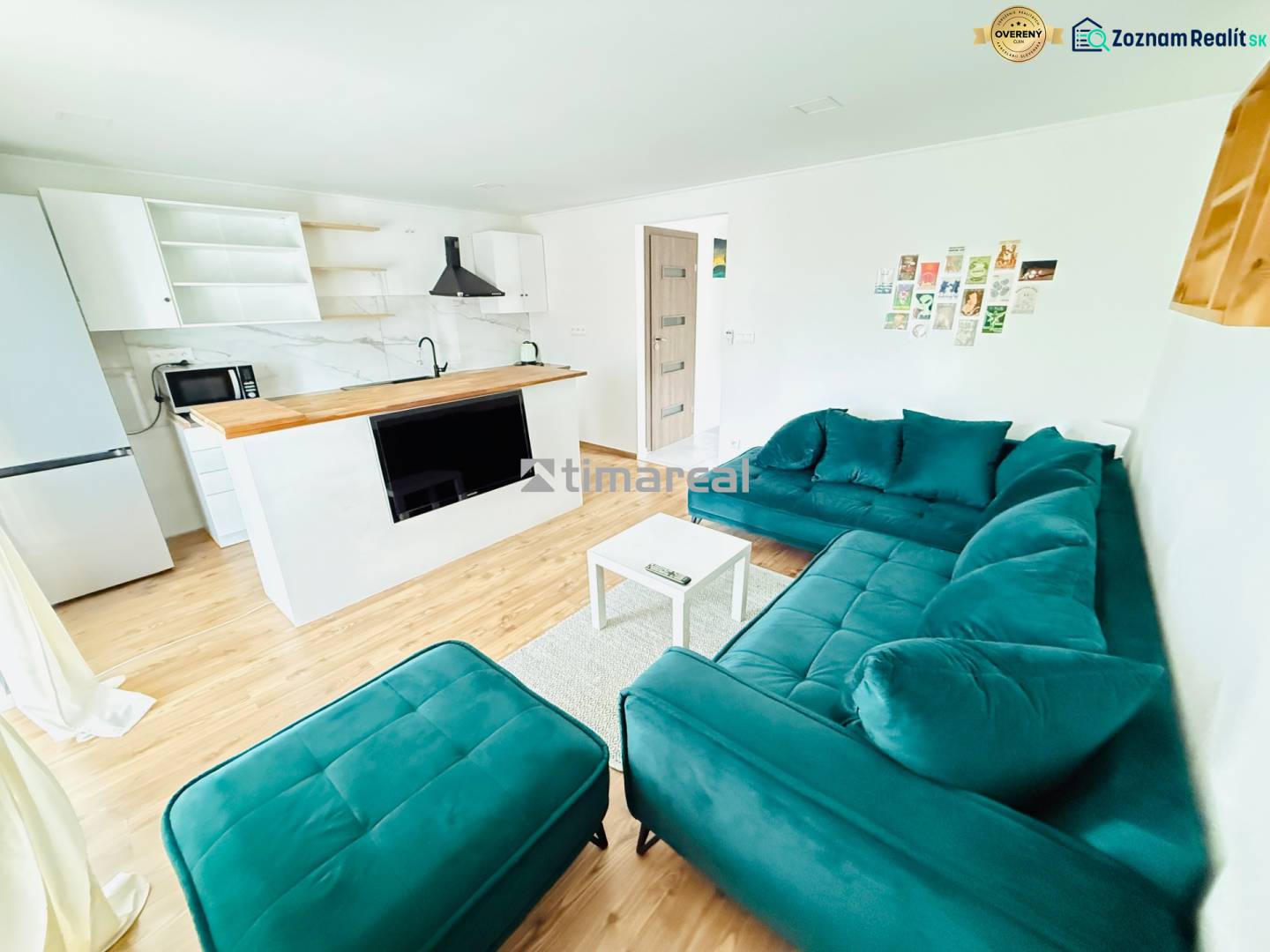 Novostavba 3i bytu s parkovaním, Dvorníky - Obývacia izba v 3-izbovom byte s podlahou s dreveným dekorom a tyrkysovou sedačkou.