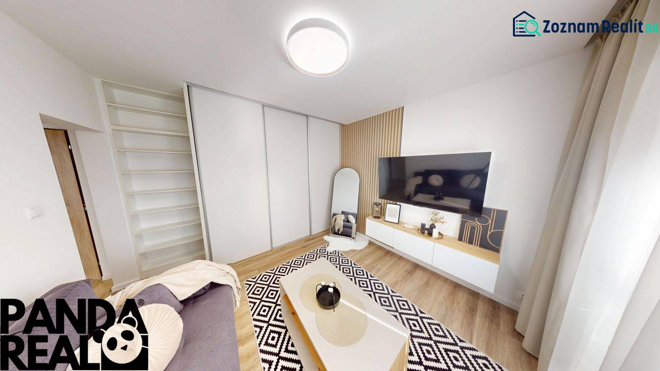 PRENÁJOM 1 IZB. BYT blízko centra, Bánovce nad Bebravou - Obývacia izba v 1-izbovom byte s TV, zrkadlom a podlahou s dreveným dekorom.