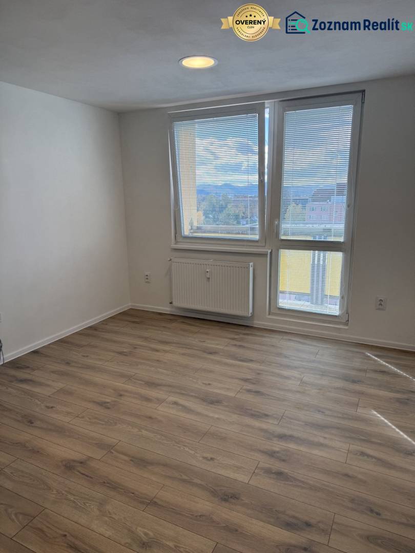  Prenájom garsónky po kompletnej rekonštrukcii (možnosť odkúpenia) - Garsónka s podlahou s dreveným dekorom a veľkým oknom, poskytujúcim výhľad do okolia.