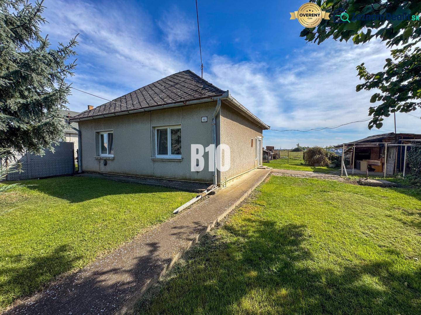 Rodinný dom s veľkým pozemkom (4641 m2)  - Ondrejovce - Rodinný dom v Ondrejovciach s trávnatým dvorom pod modrou oblohou.