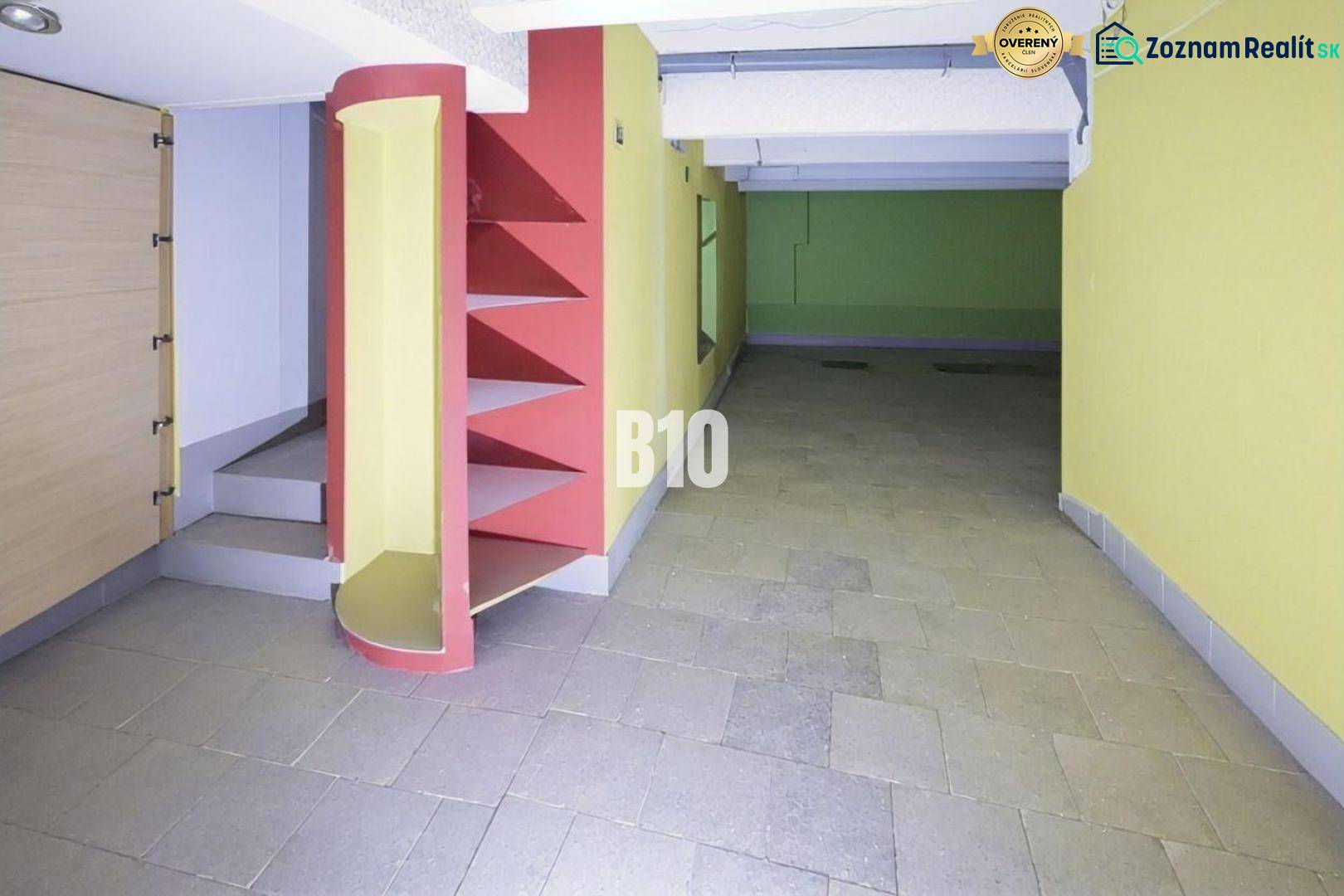 PRENÁJOM: Obchodný priestor 111m2 v centre Čadce - Interiér obchodných priestorov s farebnými stenami, regálmi a schodmi na dlažbe.