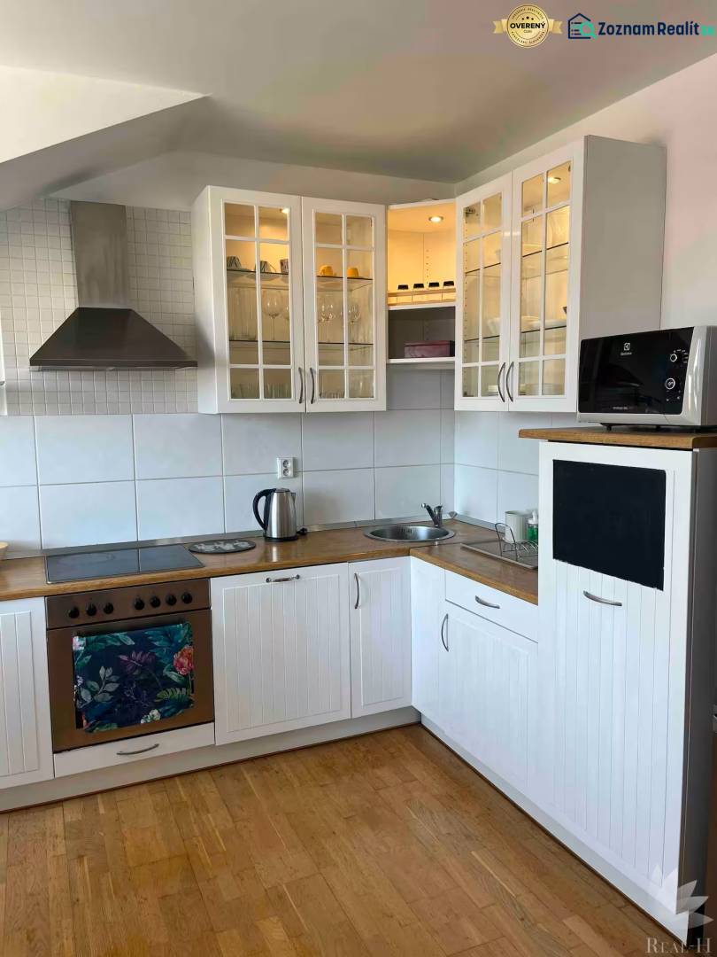 Bývanie  v Starom meste ? Jedinečná príležitosť skvelého bytu - Kuchyňa v 3-izbovom byte s drevenou podlahou, bielymi skrinkami a úložným priestorom.