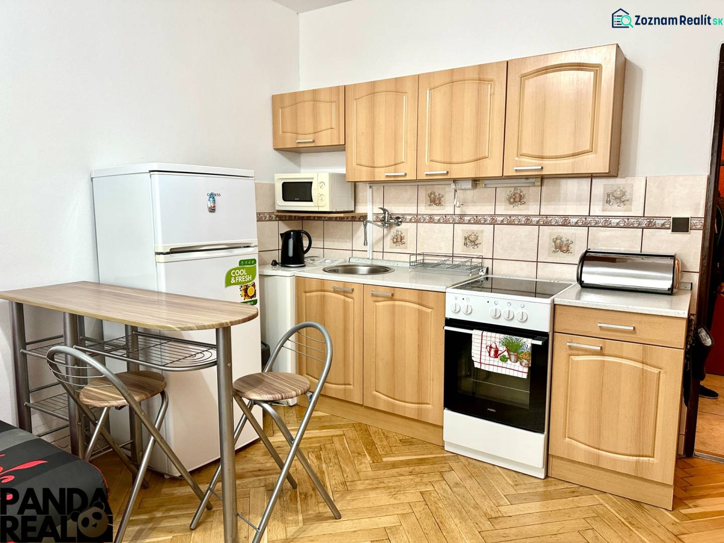 GARSONKA NA PRENÁJOM – VOĽNÁ IHNEĎ (sídlisko Východ) - Kuchyňa v garsónke s podlahou s dreveným dekorom, so spotrebičmi a sedením.