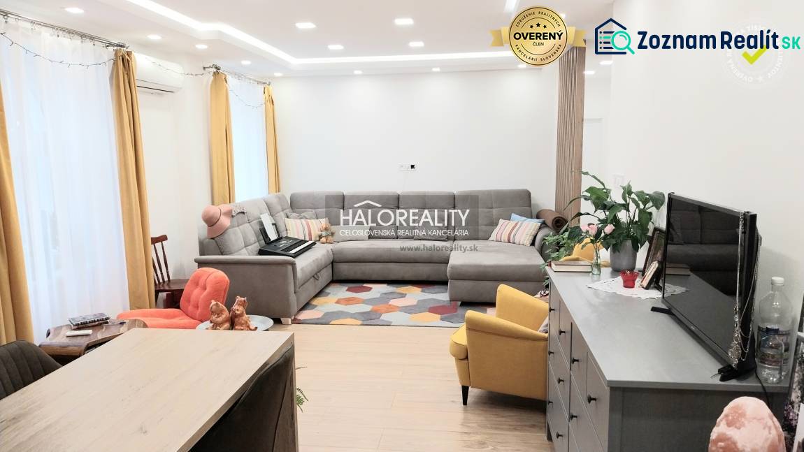 Predaj, trojizbový byt Komárno - Obývacia izba v 3-izbovom byte s podlahou s dreveným dekorom, sivou sedačkou a žltým kreslom.