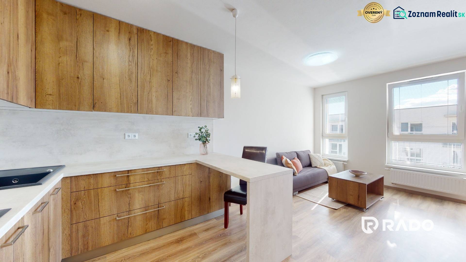 Nájom garsónka, 34 m2 | kryté parkovanie | Odevná, Trenčín - Kuchynská časť v garsónke s drevenými skrinkami, sedačkou a stolíkom, svetlá atmosféra.