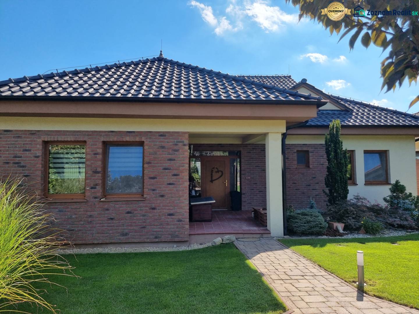 PREDAJ - Exkluzívny rodinný dom - Nitra, Zobor - Rodinný dom v Nitre s tehlovým obložením a šikmou strechou, lemovaný zeleňou.