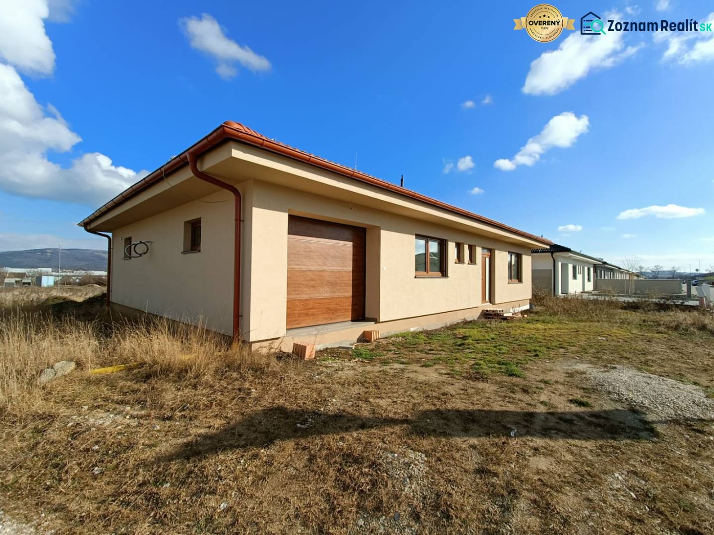 PREDAJ - 4 izbový holodom s veľkou garážou , Lužianky, Smreková ulica - Jednopodlažný rodinný dom s červenou strechou, obklopený prírodou a trávnatými plochami.