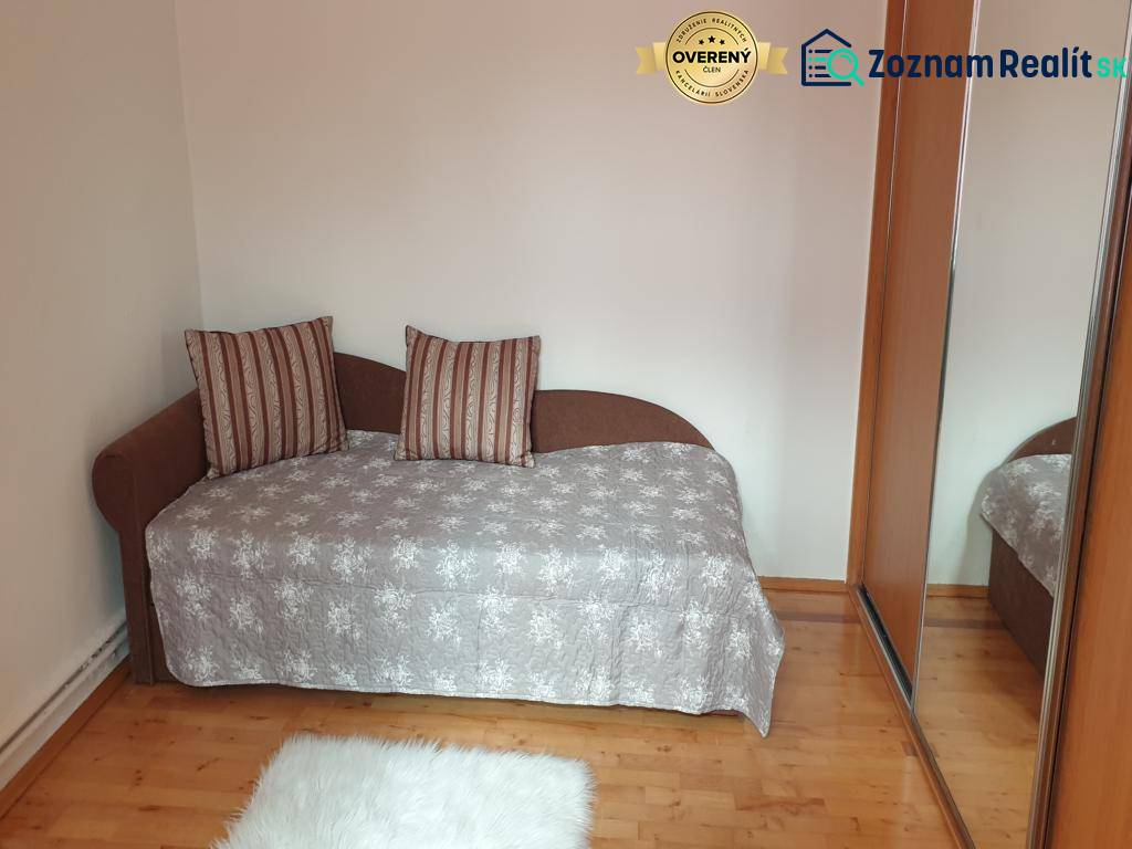 Novinka: Praktický byt v širšom centre. Mestská ul. Províziu neplatíte - Izba v 2-izbovom byte s pohovkou, zrkadlovou skriňou a podlahou s dreveným dekorom.