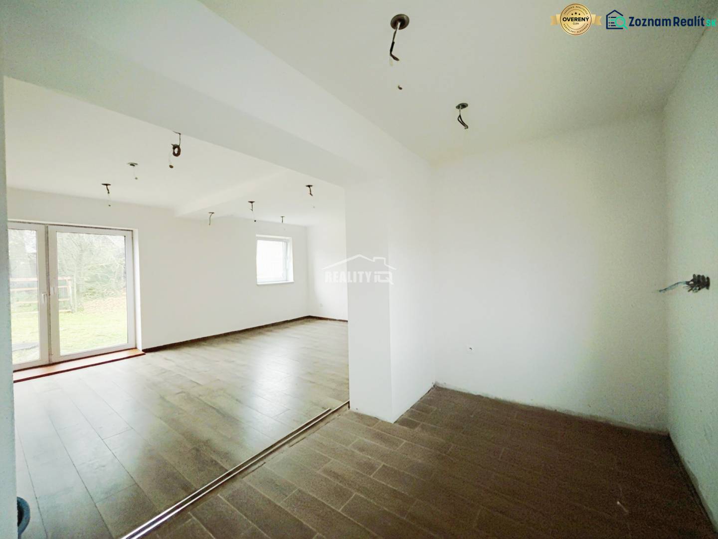 REZERVOVANÉ |Exkluzívne na predaj rodinný dom, Kolárovice (okres Bytča - Interiér rodinného domu s podlahou s dreveným dekorom a veľkými oknami do záhrady.