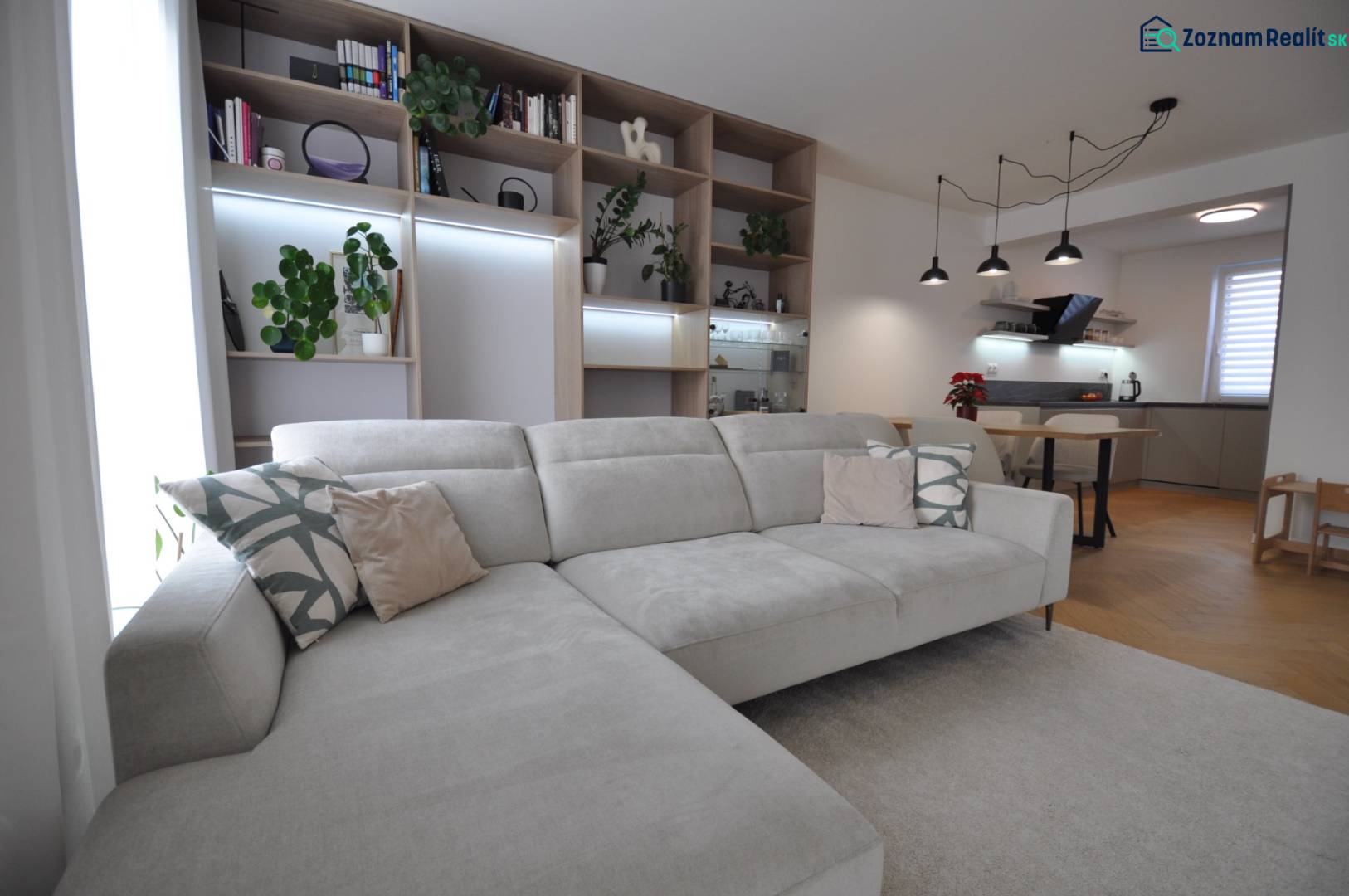 Perla v mori priemernosti - 4i prémiový RD Miloslavov - Obývacia izba s veľkou pohovkou, knižnicou a kuchynský kút v rodinnom dome.