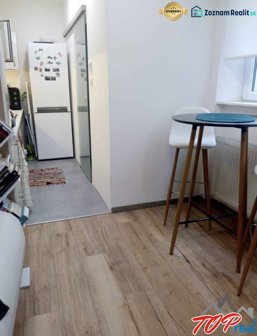 PRENÁJOM - 1,5 izbový byt Košice - Staré mesto - Kuchyňa v 1-izbovom byte s podlahou s dreveným dekorom, vysoký stolík a stoličky.