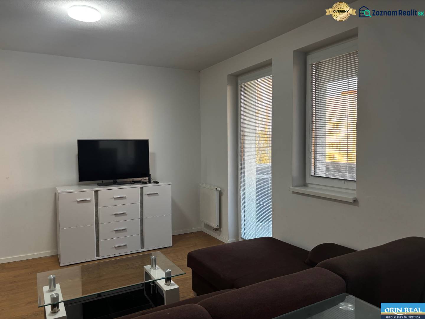 ZARIADENÁ NOVOSTAVBA 1, 5 izb. bytu- DUBOVÝ VŔŠOK - Obývačka v 2-izbovom byte s pohovkou, televízorom a podlahou s dreveným dekorom.