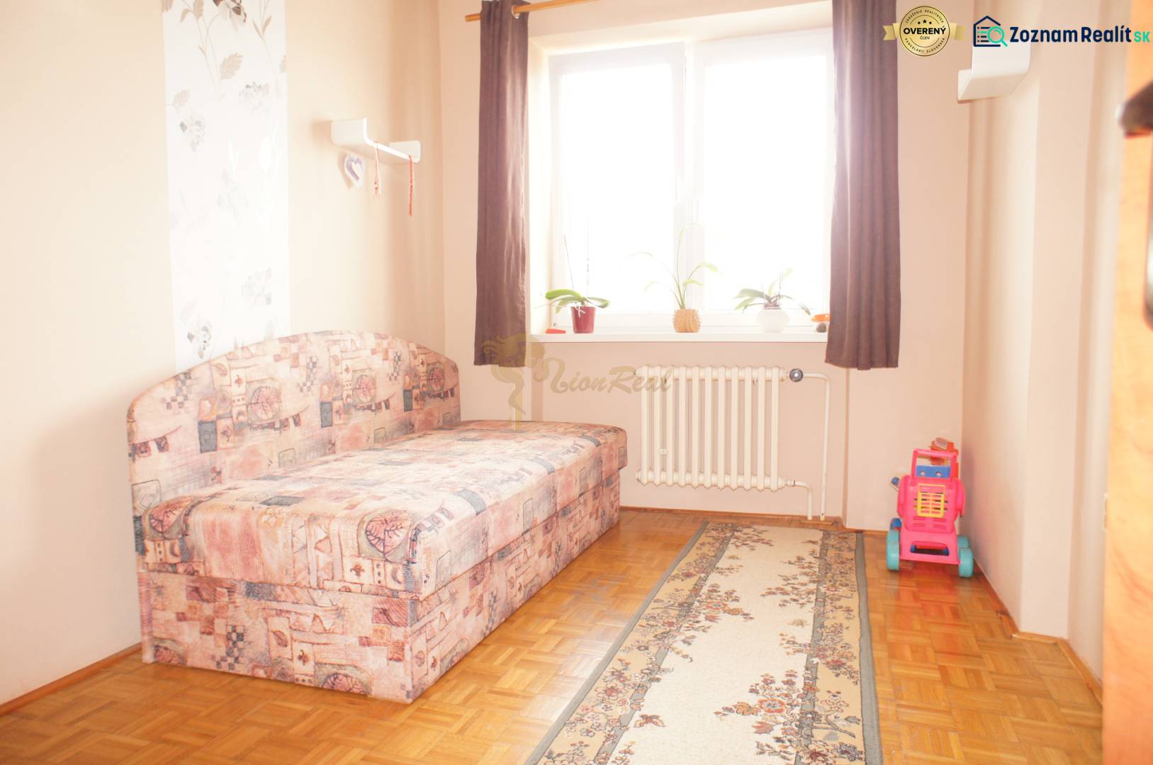 Rodinný dom v obci Čilížska Radváň s veľkým pozemkom - Izba s pohovkou, hračkami, radiátorom a dekoratívnym kobercom v rodinnom dome.