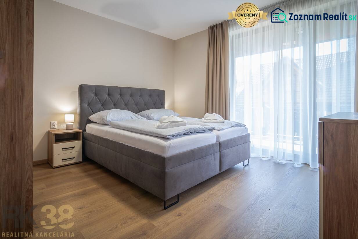 Lukratívne dvoj a štvorizbové byty v Tatranskej Lomnici na prenájom - Spálňa v 2-izbovom byte s veľkou posteľou a podlahou s dreveným dekorom.