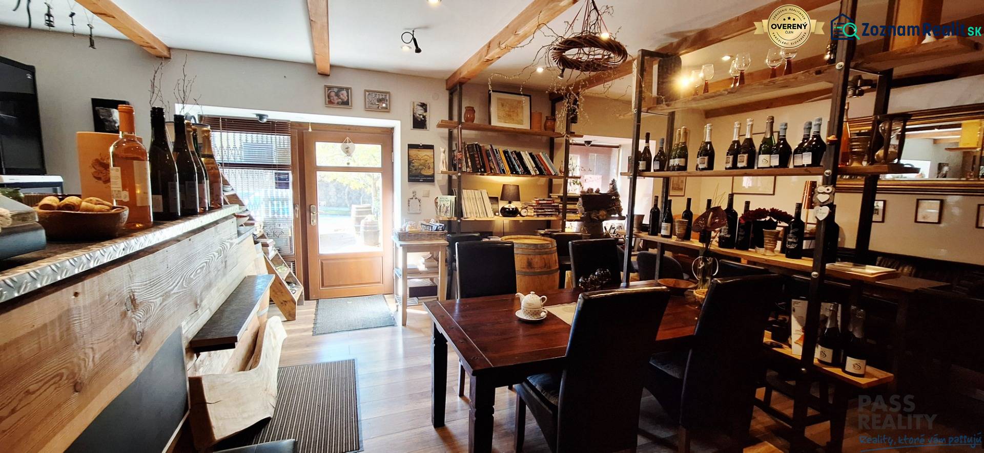 NA PRENÁJOM – odstúpenie vinotéky v srdci Starého Mesta s dušou vína - Interiér obchodných priestorov s barom, stolom a vínnymi policami, podlaha s dreveným dekorom.