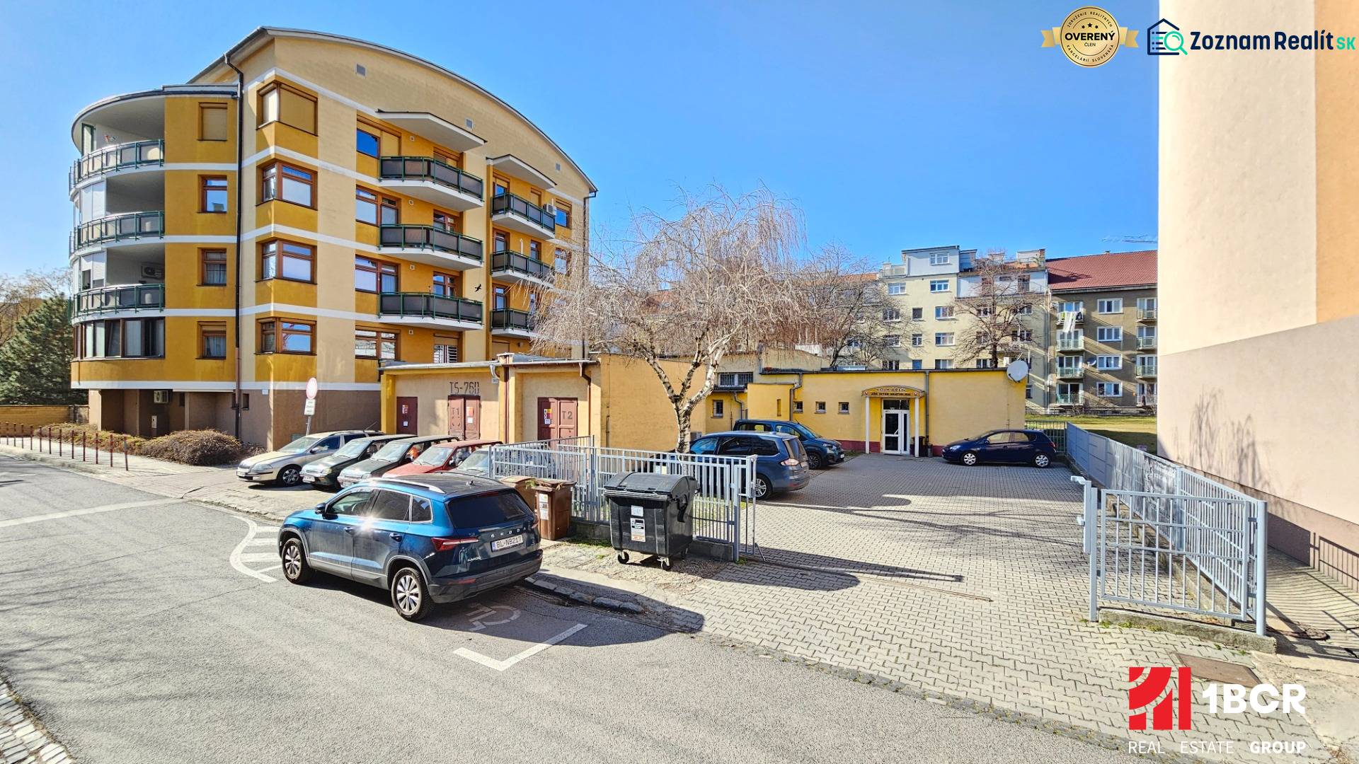 VIACÚČELOVÁ BUDOVA  - OBJEKT KOLKÁREŇ - TURČIANSKA, BRATISLAVA - Parkovanie a žltá budova na ulici Turčianska, s bytovými domami v pozadí.