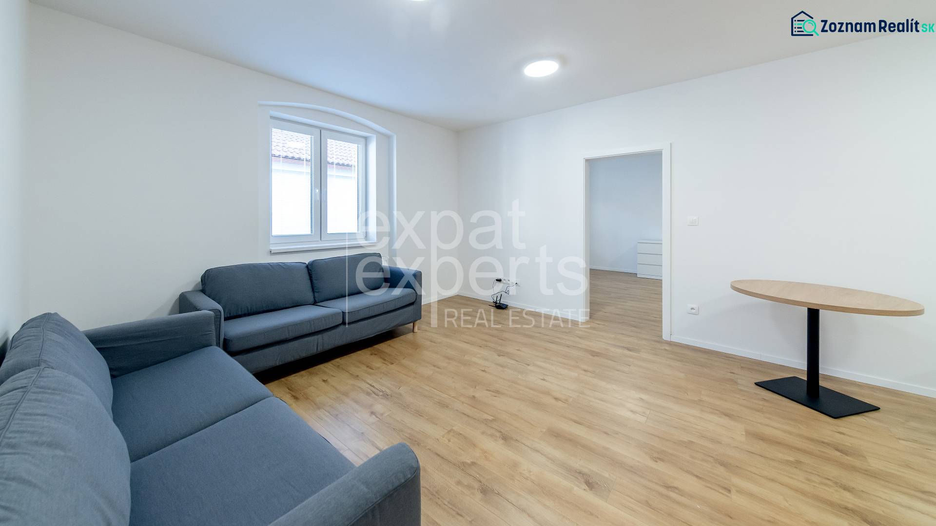 Krásny, priestranný 3i byt 71m2, v tichom dvore, úplne nový - Obývacia izba s modrými sedačkami a stolom na podlahe s dreveným dekorom.