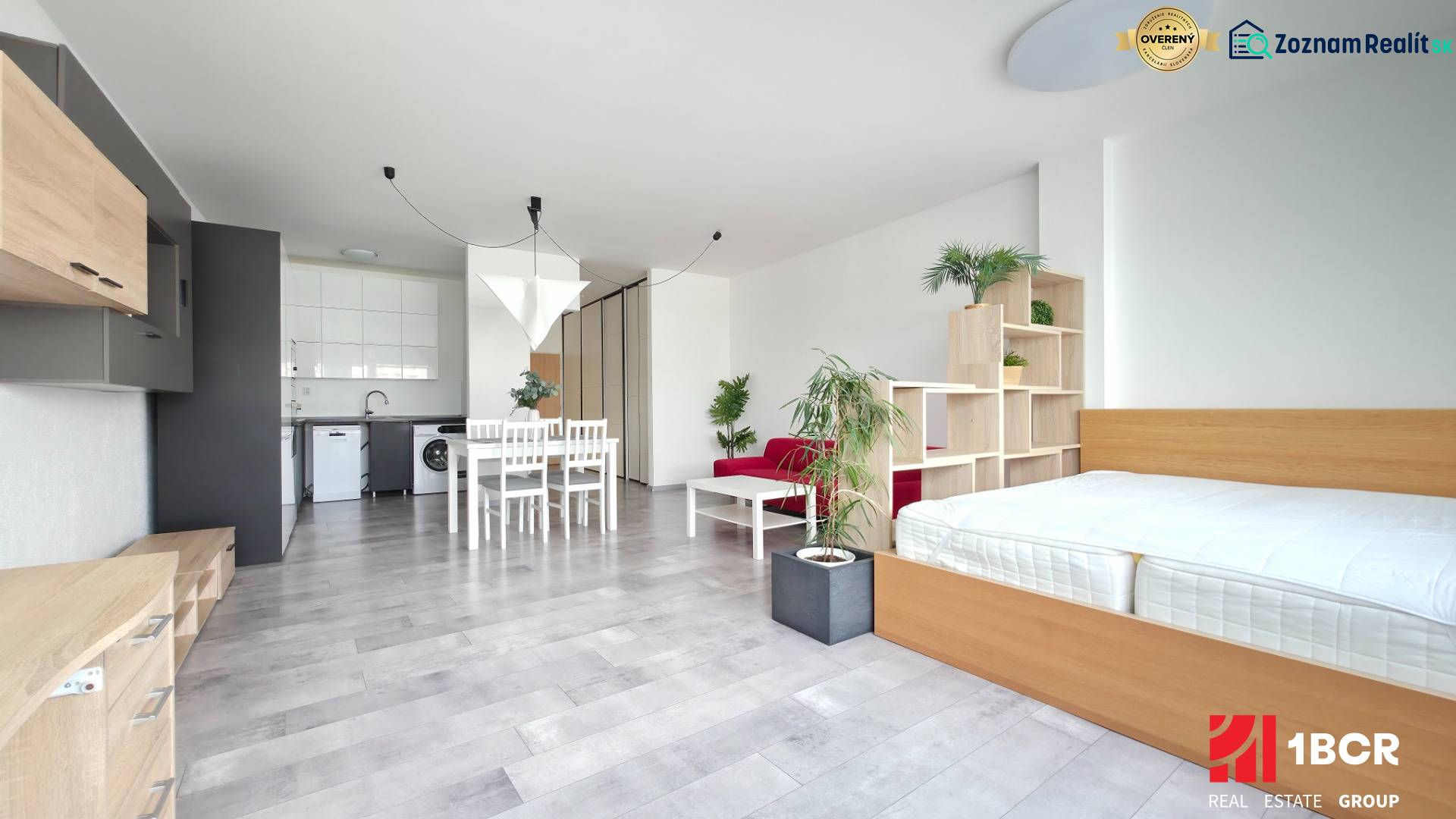 VELKOMETRÁŽNY 1 IZB.AP.BYT- TRNAVSKÁ CESTA, RUŽINOV, BRATISLAVA - Svetlý 1-izbový byt s kuchyňou, posteľou, jedálenským stolom a podlahou s dreveným dekorom.