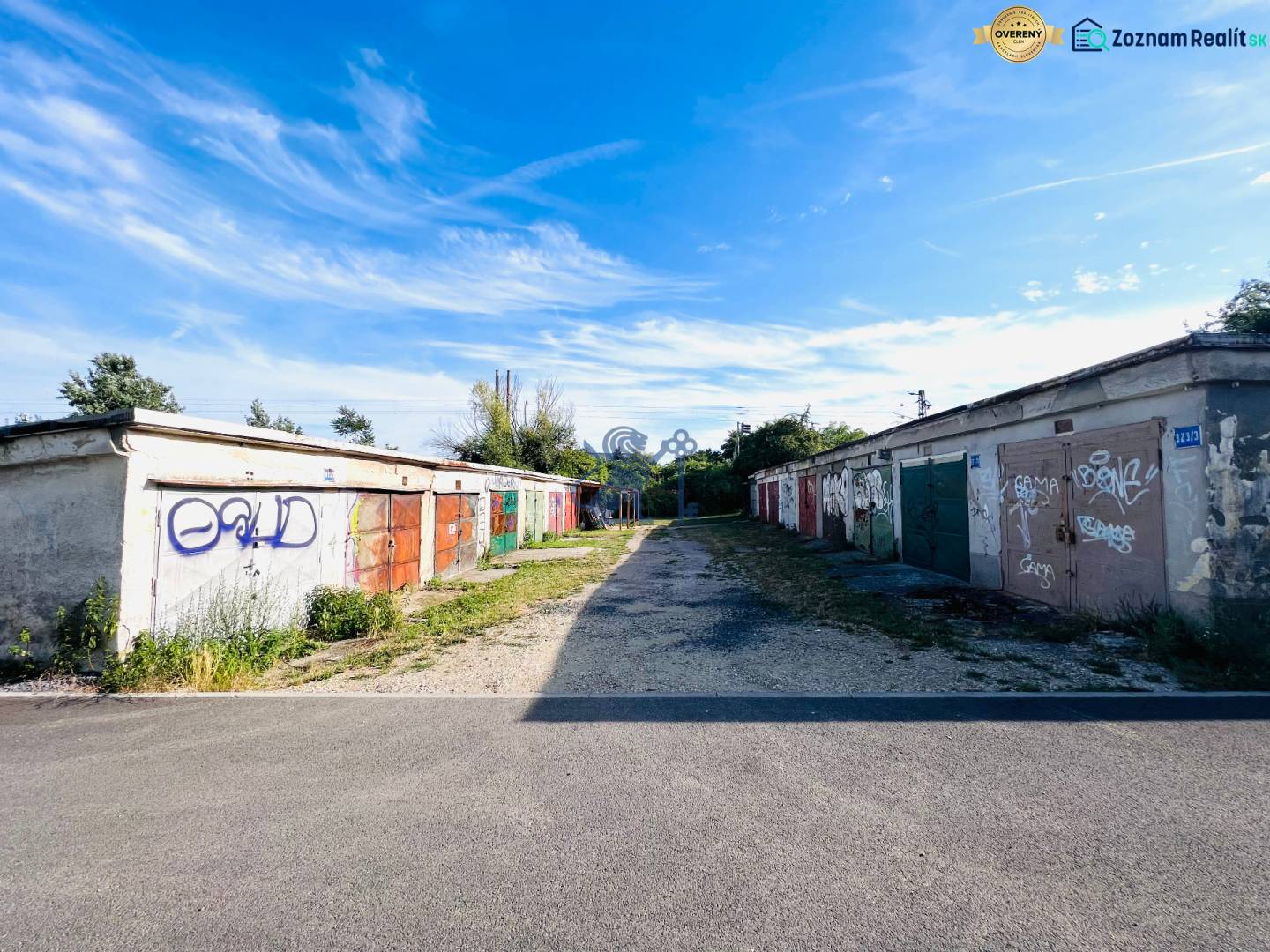Ponúkame na prenájom Garáž na Skalickej ul. Nové Mesto - Garáže na Skalickej ceste, Bratislava - Nové Mesto, pokryté graffiti pod modrou oblohou.