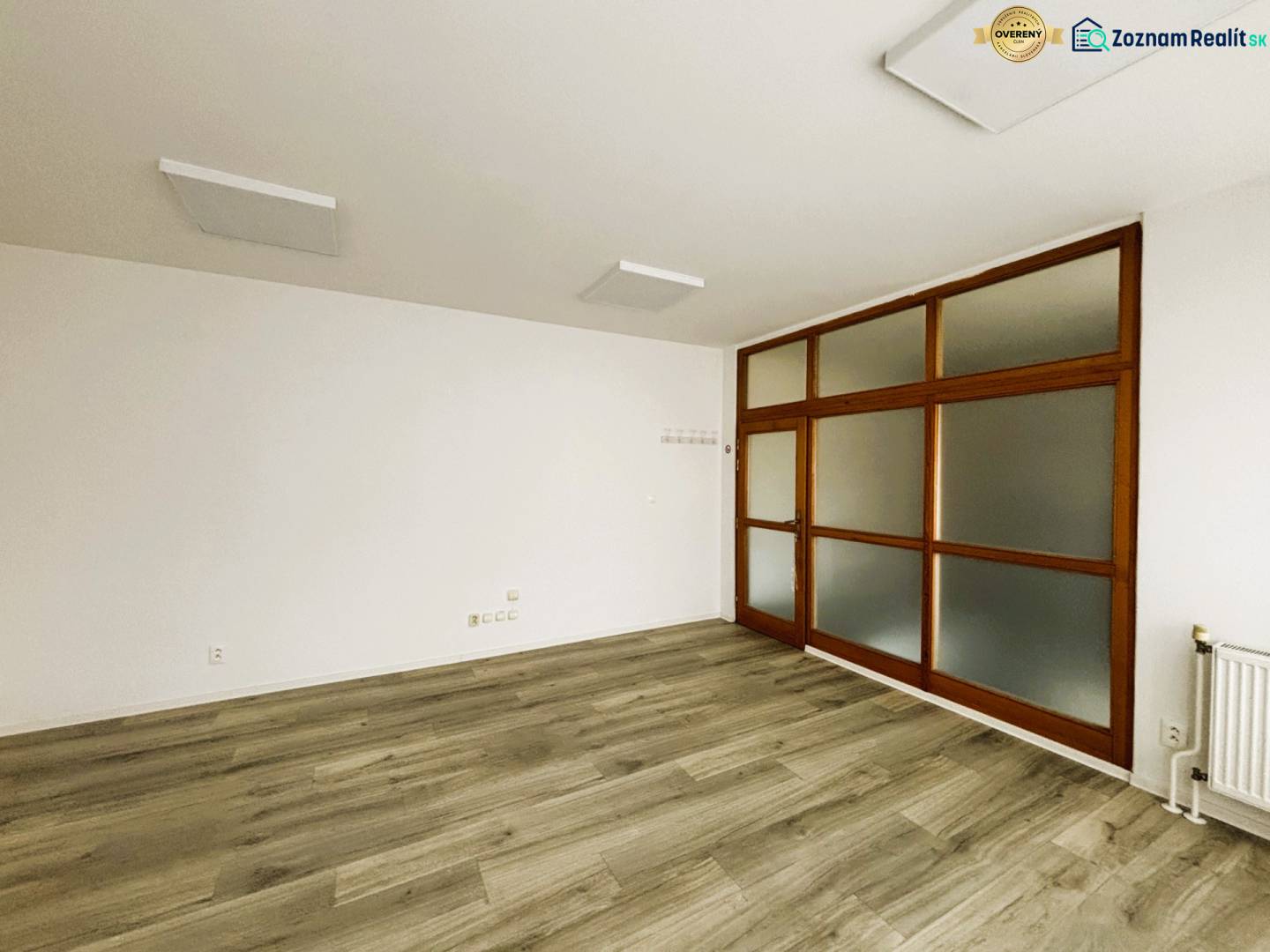 OBCHODNÝ PRIESTOR V CENTRE TRENČÍNA, 25 m2, poschodie - Obchodné priestory s bielymi stenami a podlahou s dreveným dekorom, presklené dvere.