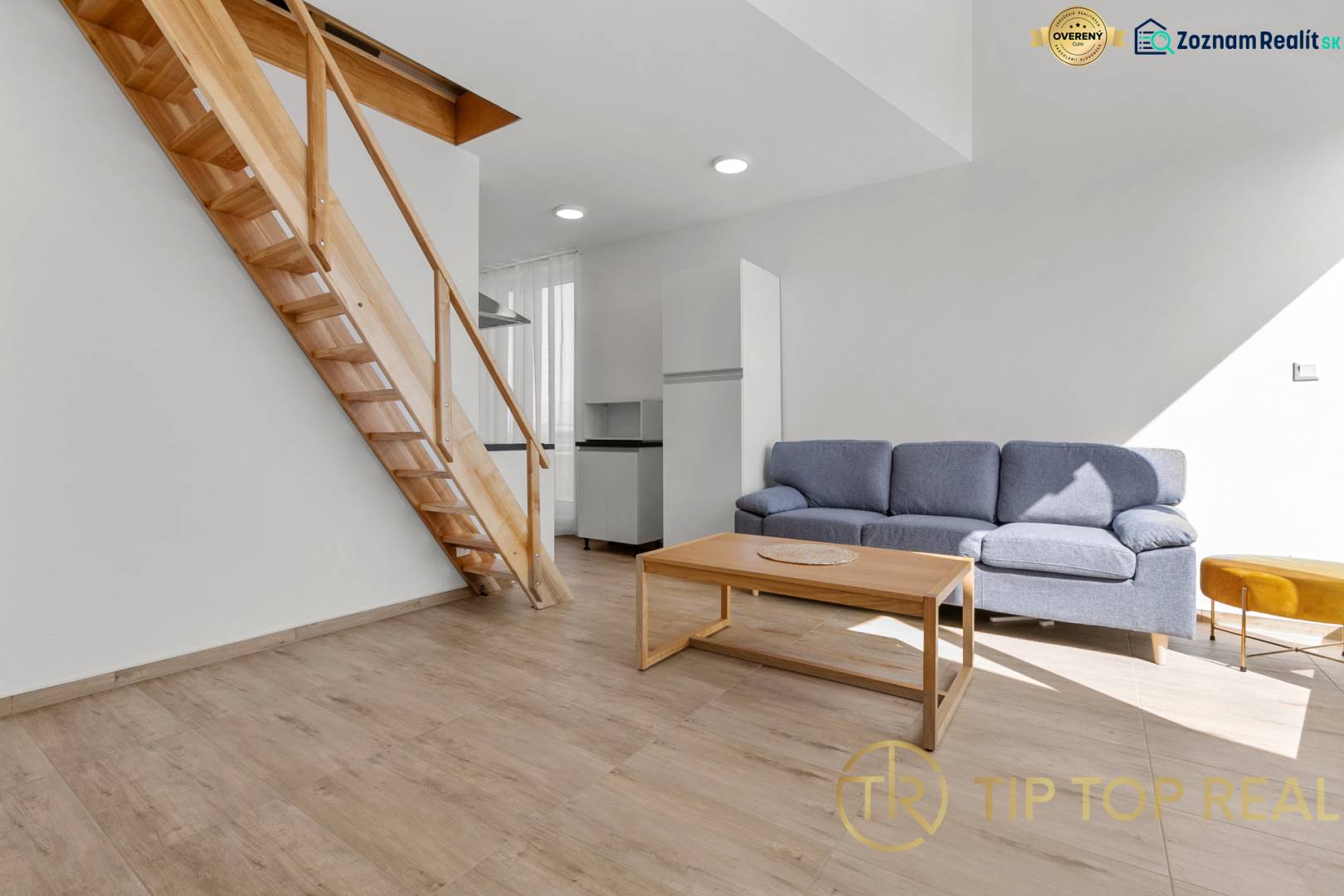 OPAL - NOVÝ a KOMPLETNE ZARIADENÝ 2,5-izbový byt s LODŽIOU a PARKOVANÍ - Obývacia izba v 2-izbovom byte s podlahou s dreveným dekorom, schodmi a šedou sedačkou.