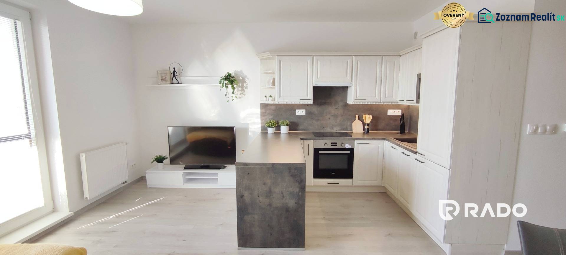 | 2-izbový byt, ul. Predmerského VINOHRADY | Trenčín  - Obývacia izba s kuchynským kútom, svetlá podlaha s dreveným dekorom v 2-izbovom byte.