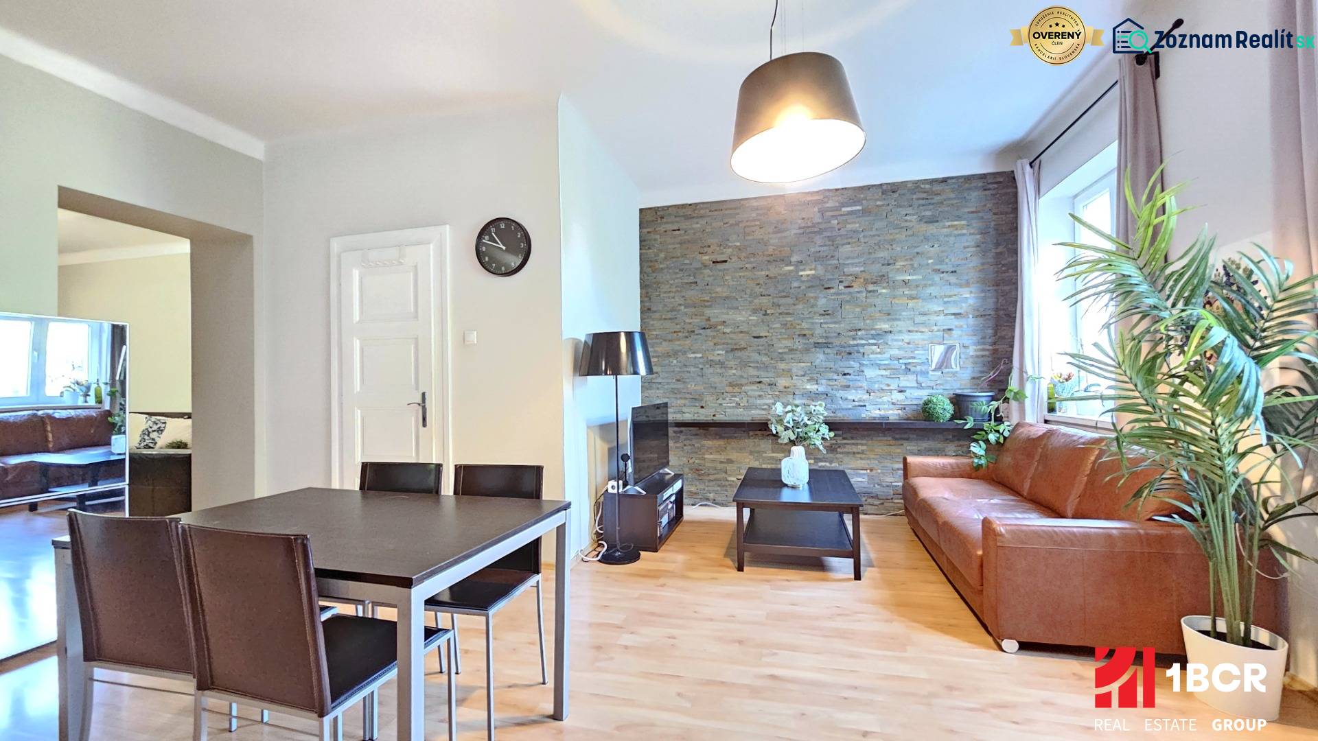 PRIESTRANNÝ 2.IZB. BYT - PIVNICA, LODŽIA - DOBROVSKÉHO, STARÉ MESTO - Interiér 2-izbového bytu s podlahou s dreveným dekorom, pohovkou a jedálenským stolom.