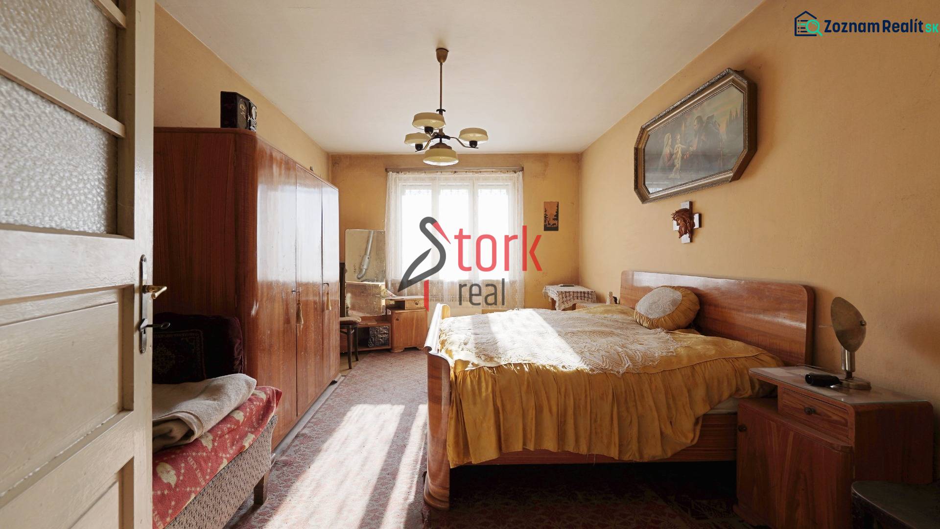Menší rodinný dom len pár metrov od centra mesta Rajec - Spálňa v rodinnom dome s nábytkom, lusterom a obrazom na stene.