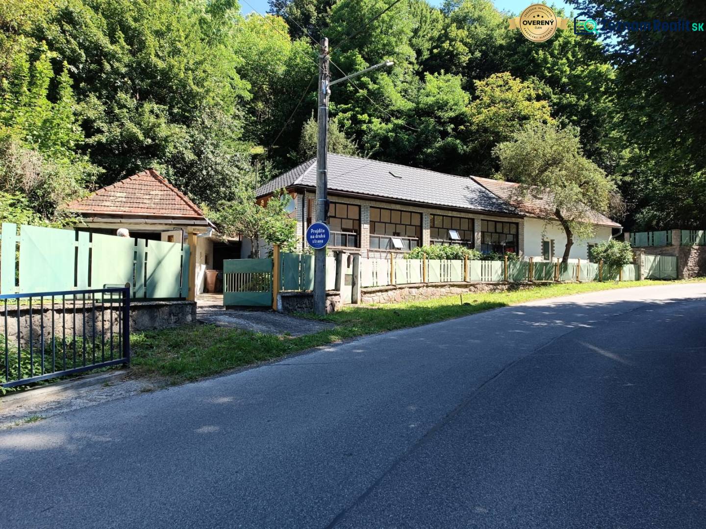 Na predaj  dom v obci Vyhne iba 400m od Vodného raja.  - Rodinný dom na ulici Vyhne obklopený zeleňou a plotmi, slnečný deň.
