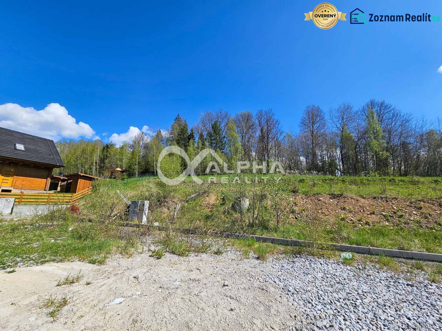 Stavebné pozemky v lokalite Slnečná úboč, Levočská Dolina - Pozemky na bývanie v Levočskej doline, Levoča, obklopené lesom a modrou oblohou.