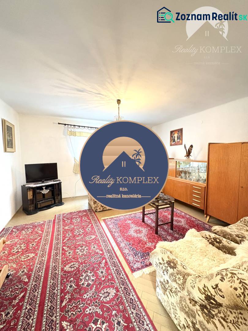 IBA U NÁS !!! ponúka EXKLUZÍVNE na predaj rodin - Obývačka v rodinnom dome s kobercom, televízorom a dreveným dekorom nábytku.