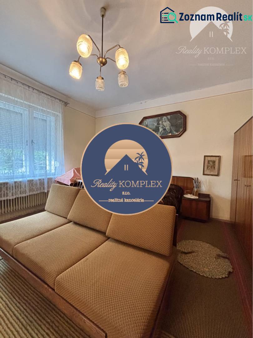 Vám ponúka na predaj 4 izbový rodinný dom  s r - Obývacia izba v rodinnom dome s pohovkou, lustrom a svetlou záclonou na okne.