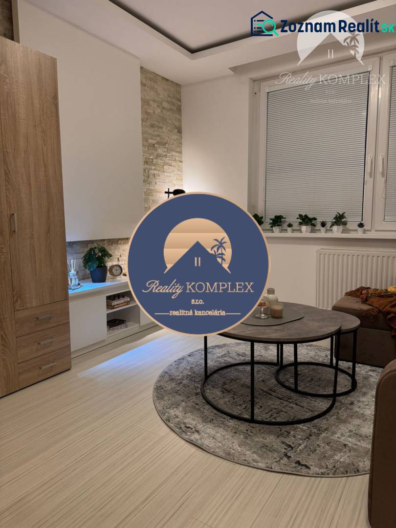 Vám ponúka garsonku vo VYHĽADÁVANEJ lokalite m - Obývacia izba s gaučom, konferenčným stolíkom a podlahou s dreveným dekorom v rekreačnom apartmáne.