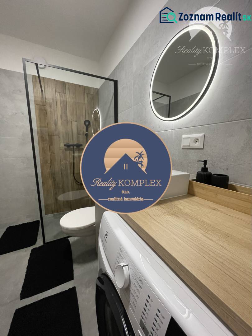 Vám ponúka na Prenájom 2-izbový byt s loggiou  - Kúpeľňa v 2-izbovom byte s práčkou, sprchovým kútom a podlahou s dreveným dekorom.