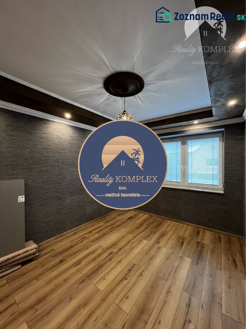 Vám ponúka na PREDAJ kompletne zrekonštruovaný  - Miestnosť rodinného domu s tmavou stenou, podlahou s dreveným dekorom a zaujímavým stropom.