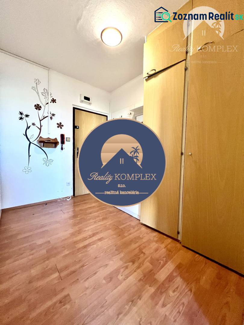 Ponúka na PREDAJ 1 izbový byt v Komárne - Interiér 1-izbového bytu s podlahou s dreveným dekorom a vstavanou skriňou.
