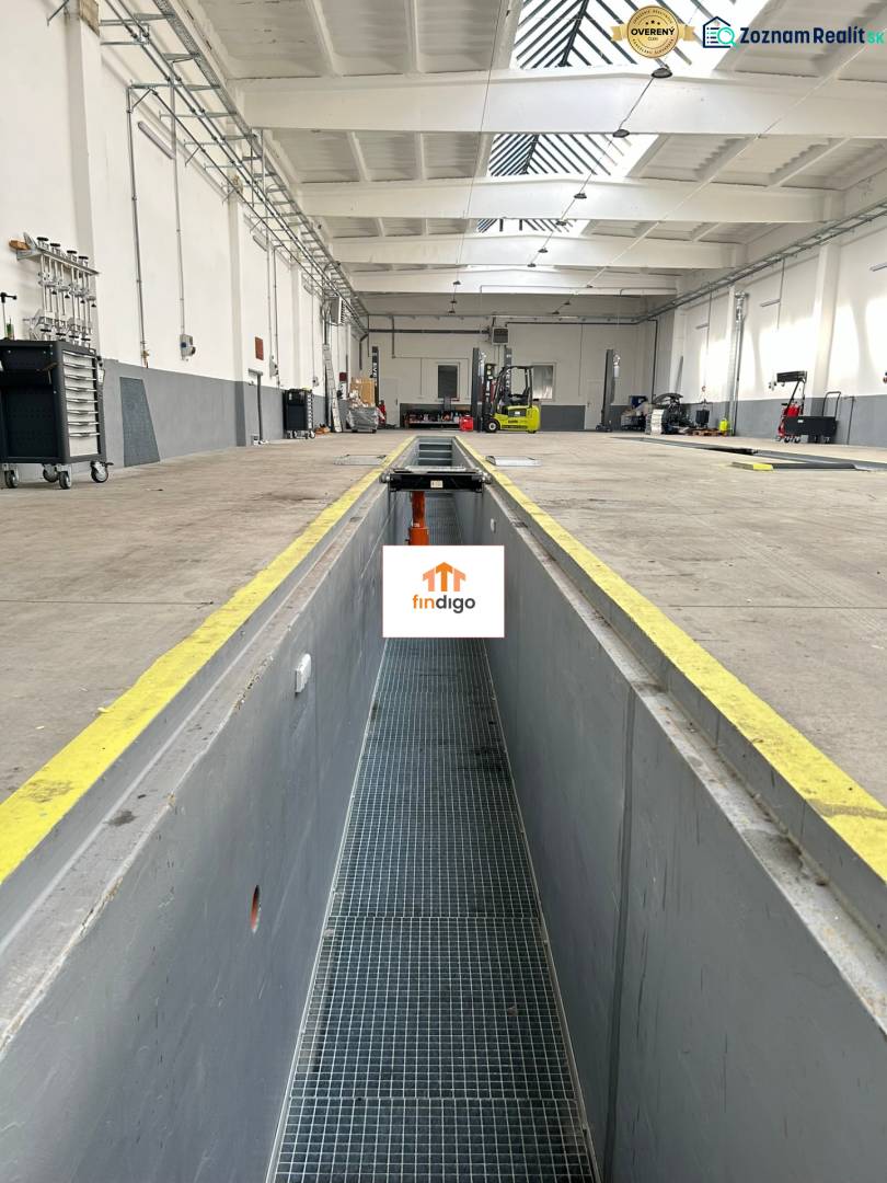 Autoservis s výbavou pre vozidlá v uzavretom priemyselnom areáli - HC - Interiér budovy s vysokým stropom, servisnou jamou, náradím a vybavením.