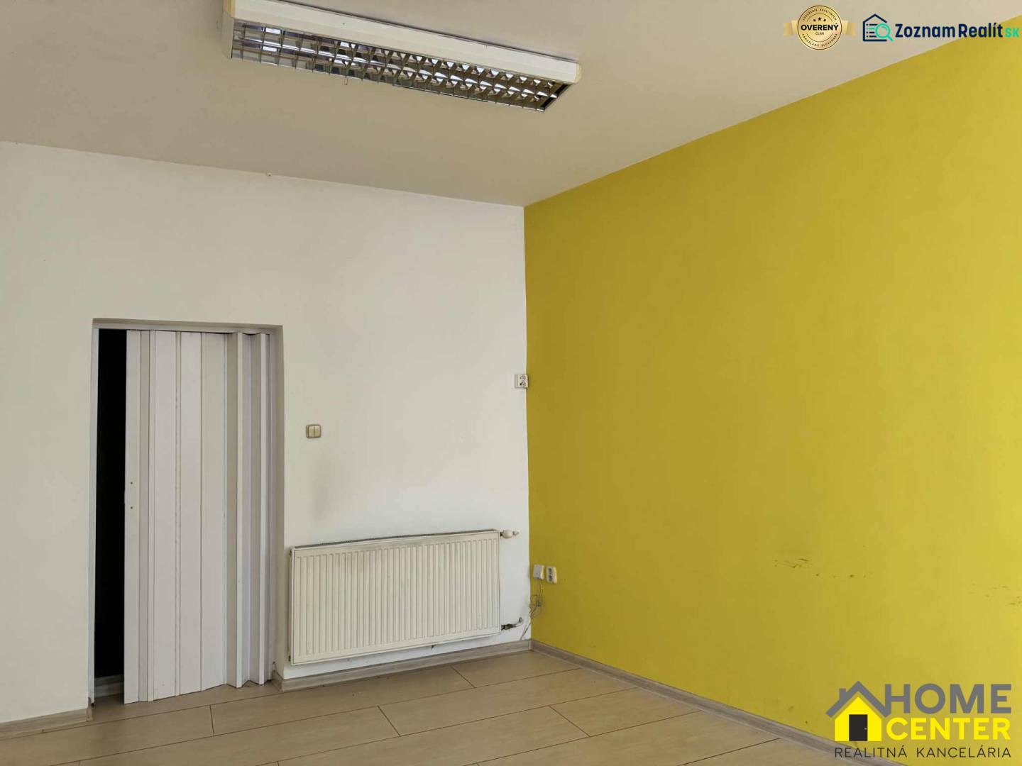 PRENÁJOM obchodný priestor/kancelária v priamom centre - KOMÁRNO - Interiér obchodných priestorov s podlahou s dreveným dekorom a žltou stenou.